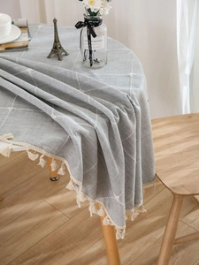 Close-up of gray checkered linen tablecloth with delicate beige fringe tassels