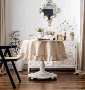 Detailed view of beige linen round tablecloth with elegant ruffled edge draping naturally