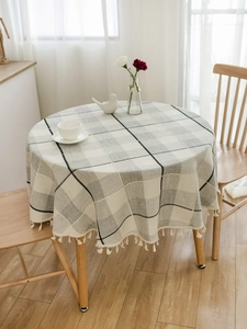 Detail of round linen-textured plaid tablecloth with white elegant tassel fringe edges