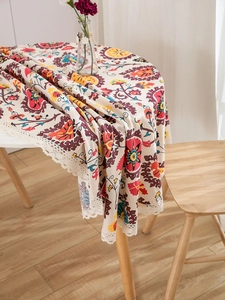 Detail of bohemian floral pattern tablecloth with cream lace trim on a round table