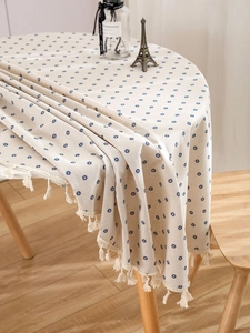 Detail of round cotton linen tablecloth with blue floral print and fringe tassels