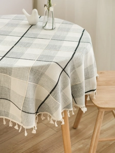Close-up of gray checkered round tablecloth with delicate white fringe tassels