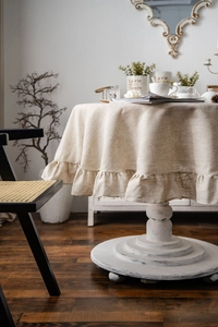 Detailed view of beige linen blend round tablecloth with elegant ruffled edges and drape