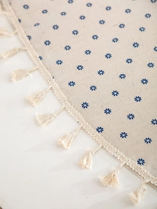 Detailed view of beige cotton linen tablecloth with blue floral print and fringe edges