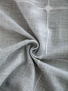 Macro shot of gray linen-blend tablecloth with white cross-stitch embroidery detail
