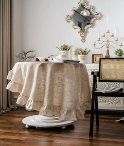 Detailed view of beige ruffled edge tablecloth with natural linen fiber texture