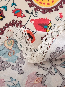 Close-up of Bohemian floral print tablecloth with detailed white lace embroidery edge