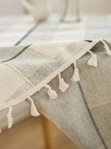 Close-up of classic grey plaid tablecloth texture with fringe trim detail