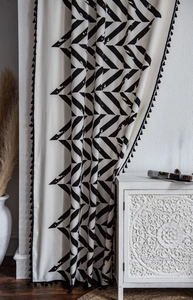 Detailed view of bohemian black and white geometric arrow pattern curtain with tassels