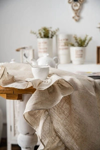 Close-up of a natural beige linen-blend tablecloth featuring elegant ruffled edges