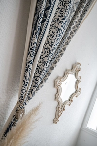 Close-up of blue and white damask cotton linen curtain with wooden deer tieback