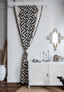 Detail of cotton linen curtain with black geometric patterns and tassels showing elk ties