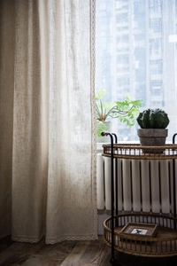 Detailed close-up of beige linen curtain fabric featuring elegant lace crochet borders