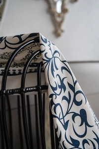 Detail showing navy blue damascus pattern on beige cotton linen fabric draped on chair