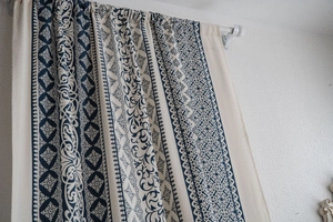 Detail of vintage blue porcelain print curtains on beige cotton linen fabric