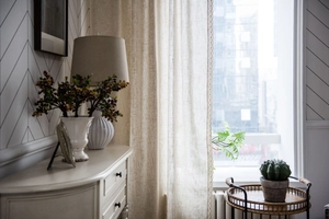 Close-up of beige linen curtains featuring delicate lace trim and natural fabric texture