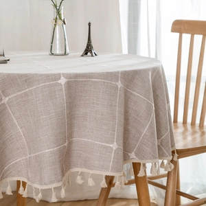 Round beige linen textured tablecloth with white plaid pattern and tassel fringe edges
