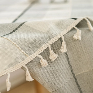 Plaid linen tablecloth in beige and grey with decorative fringe tassels for dining tables