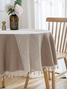 Detail of beige round tablecloth featuring geometric jacquard pattern and boho fringe tassels