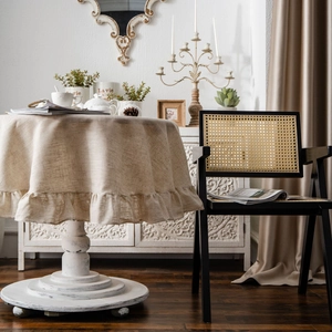 Elegant beige round linen tablecloth with ruffled edges in a French vintage home setting