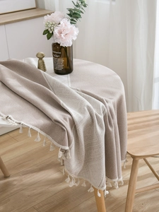 Close-up of beige geometric jacquard tablecloth with rustic white fringe tassels