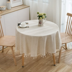 Elegant beige round linen tablecloth with handmade tassel fringe for a minimalist home decor