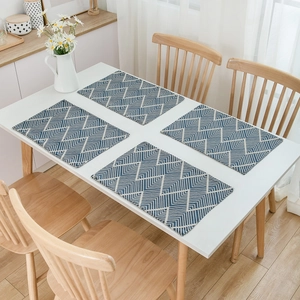 Set of 4 navy blue wave jacquard placemats with geometric patterns on a white table