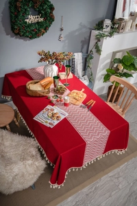 Detail of red festive tablecloth with white chevron pattern and beige tassel edges