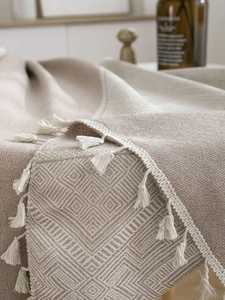 Macro shot of geometric jacquard pattern and handmade tassels on a green woven tablecloth