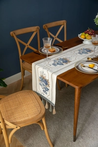 Detail of vintage European table runner with blue floral embroidery and hanging tassels