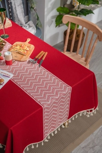 Detail of red tablecloth featuring white wavy jacquard pattern and beige tassel fringe