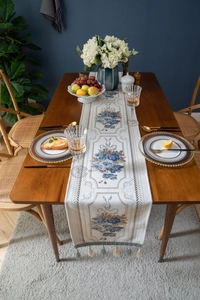 Close-up of vintage floral jacquard table runner with decorative tassels and texture