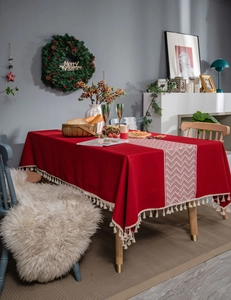 Close-up of red festive tablecloth featuring white tassels and wavy patterned runner detail