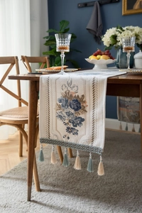 Detail of European jacquard table runner with blue floral embroidery and long tassels