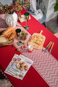 Close-up of red tablecloth and white jacquard runner with festive tassels and wavy patterns