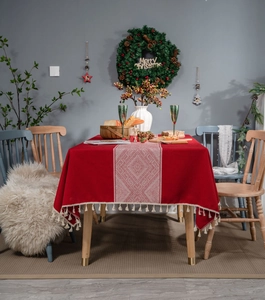 Détail de la nappe rouge festive avec motifs géométriques blancs et bords à glands