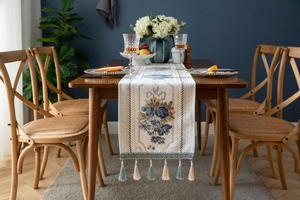 Detail of floral embroidery and blue-beige tassels on an elegant jacquard table runner
