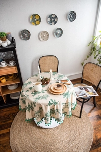 Detail of round cotton linen tablecloth with green pine tree prints and tassel trim