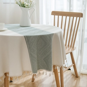 Round beige tablecloth with sage green geometric runner and elegant fringe tassel accents