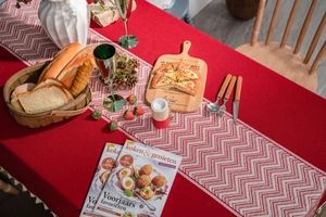 Detail of red festive tablecloth with white tassel table runner and chevron pattern