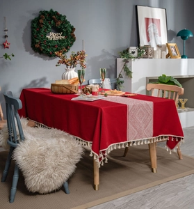Détail de nappe rouge avec chemin de table géométrique et glands décoratifs blancs