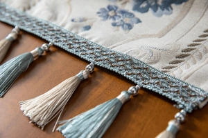 Detail of floral embroidery on cream table runner with light blue tassels and silver beads