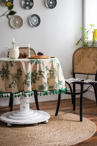 Detail of round cotton linen tablecloth with green pine print and tassel fringe edges