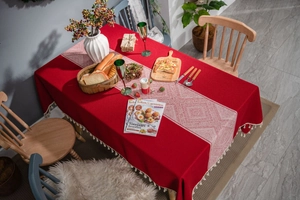 Détail de nappe rouge avec chemin de table géométrique et glands beige décoratifs