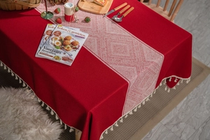 Détail de nappe jacquard rouge avec des pompons blancs et des motifs géométriques