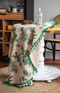 Close-up of green pine branch print on linen tablecloth with handmade fringe edge