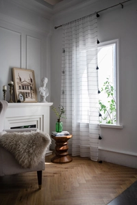 Detail of white striped sheer curtain with black decorative tassels in modern living room
