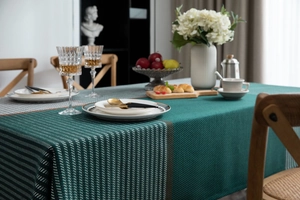 Detail of dark green woven tablecloth with textured jacquard and striped edge design