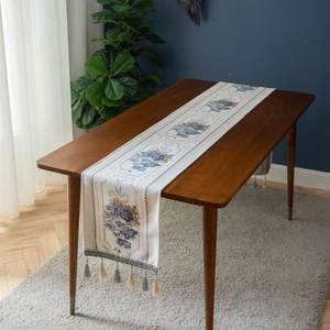 European jacquard table runner with blue floral patterns and tassels on wood table