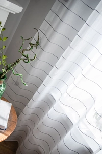 Detail of white semi-transparent striped curtain with black horizontal fringe patterns